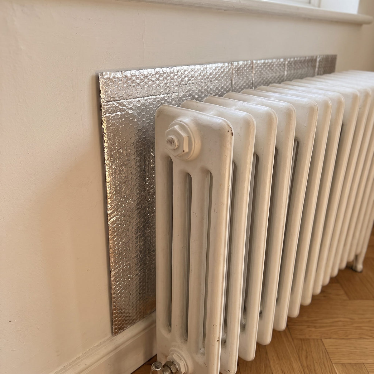 Panneau réflecteur derrière un radiateur en fonte